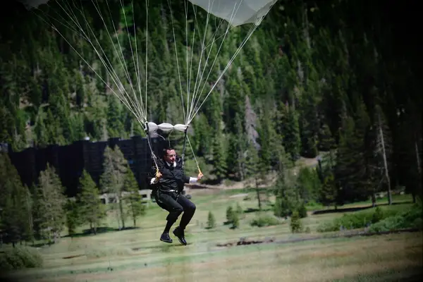 Groom parachuting into wedding reception.