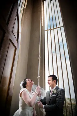 Bride and groom pulling a church bell rope.