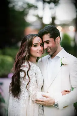 Couple hugging and wearing all-white wedding fashion