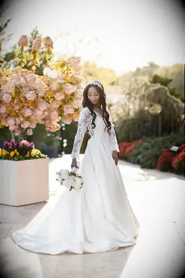 Bride in long-sleeve wedding dress holding white bouquet