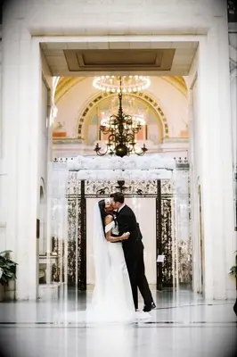 Ceremony first kiss in front of acrylic arch with white flowers