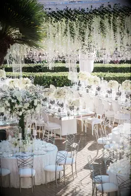 Glam outdoor wedding with hanging floral designs and dramatic tables capes