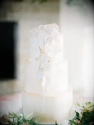 Three-tier white wedding cake with white floral decoration