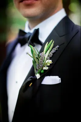 lavender and greenery boutonniere pinned to black tuxedo jacket with white pocket square