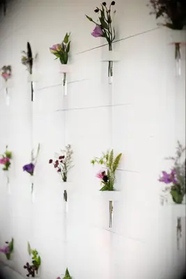 wedding escort card display featuring white shiplap wall decorated with purple wildflowers in glass bud vases 