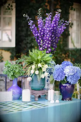wedding welcome table with purple stock flowers, blue hydrangeas and white tulips in assorted ceramic chinoiserie vases