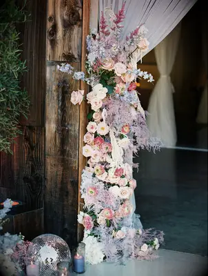 wedding venue entrance decor with blush pink roses, light purple painted greenery and silver disco balls