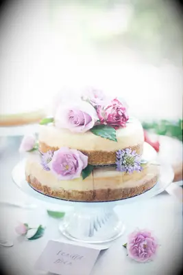 two tier nakes wedding cake decorated with light purple roses 