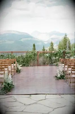A vibrant outdoor wedding terrace, complete with wooden folding chairs and white floral arrangements.