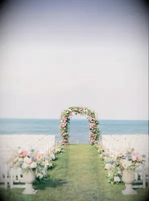 A vibrant pink floral arch welcomes guests to their seats.