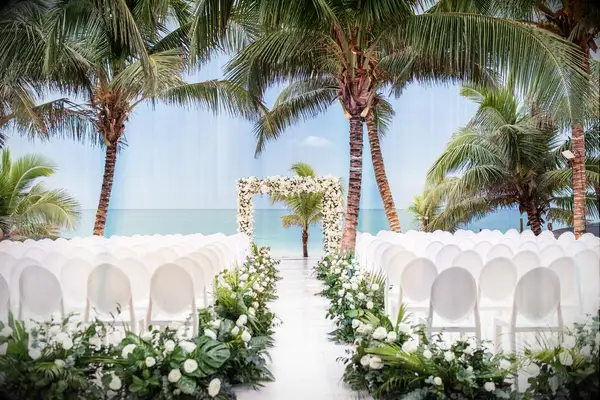A beachside tropical wedding with a beautiful white floral archway.