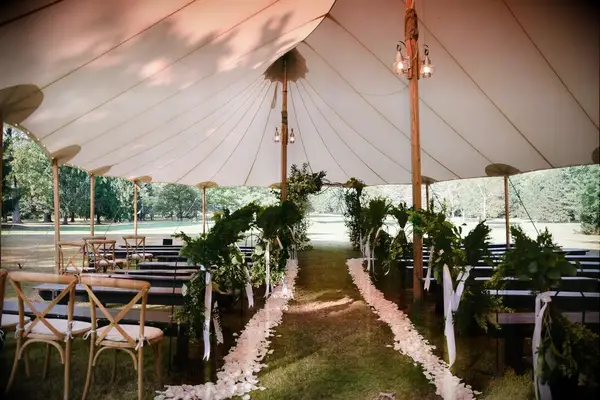 A beautiful tented ceremony site, complete with white flowers along the aisle.