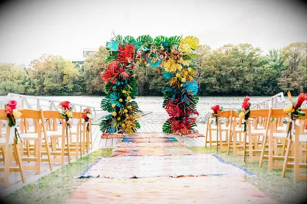 This modern tropical wedding arch is complemented by shabby-chic rugs along the aisle.