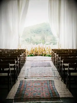 A romantic wedding aisle, with vintage rugs leading guests to their seats.