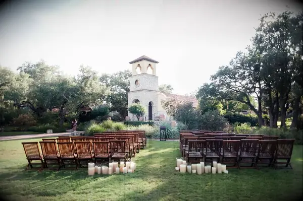 An outdoor, Italian-inspired ceremony site with wooden chairs and candles.