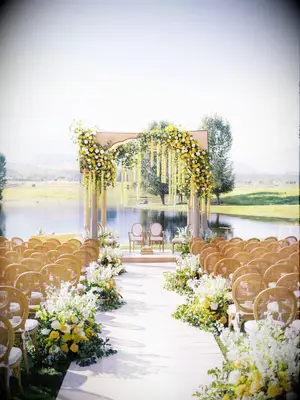 What a dreamy scene: yellow and white flowers cascade down the wedding arch and lead guests towards the altar.