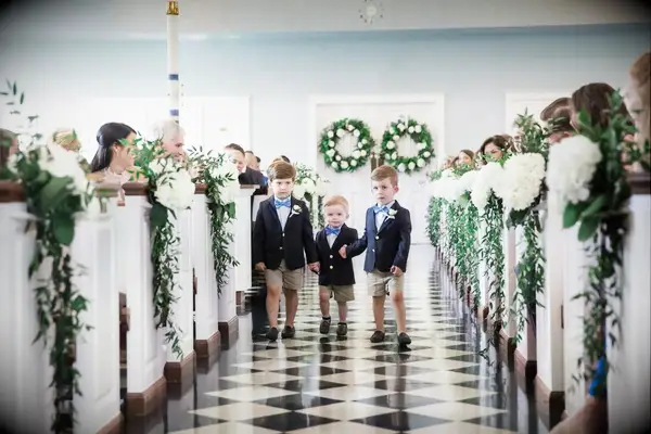 White hydrangeas and delicate greenery guide a trio of ringbearers up the wedding aisle.
