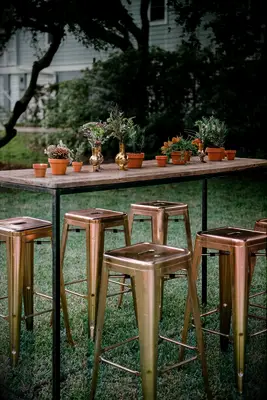 Tall table with potted plant centerpieces and industrial bar stools