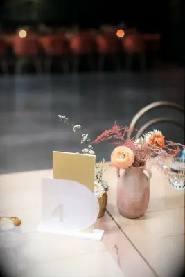 Acrylic table number and small clay vase with ranunculus blooms