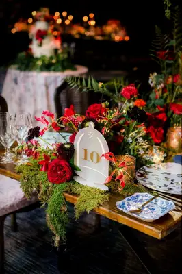 Acrylic table number surrounded by red roses and moss
