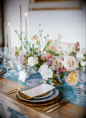 Floral centerpiece on farm table with blue runner