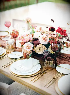 Vibrant pink-and-burgundy floral centerpiece on farm table