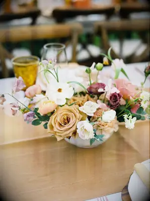 Floral centerpiece on top of mustard-yellow table runner