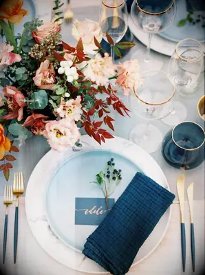Brown floral arrangement beside blue place setting