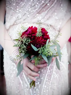 A bride holds this vibrant wine-colored bouquet.
