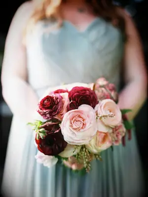 A bridesmaid holds this wine and peach-toned bouquet.