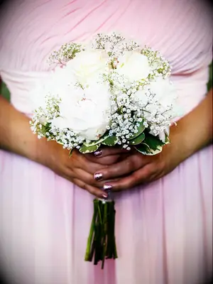 A bridesmaid holds with white and pale yellow bouquet.