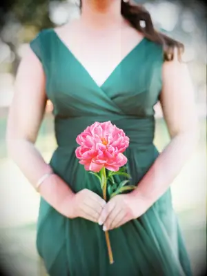 A bridesmaid holds a single vibrant pink flower.