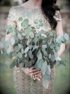 A bridesmaid holds a eucalyptus bouquet.
