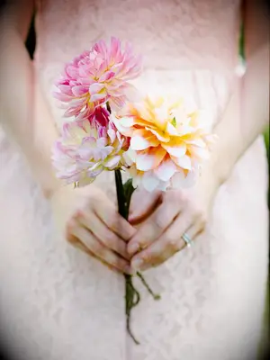 A bride holds this springtime bouquet of peach and pink flowers.