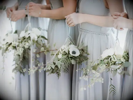 Bridesmaids hold these pale white and green bouquets.