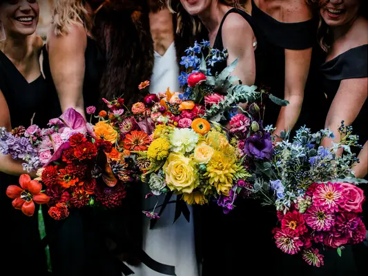 Bridesmaids hold a rainbow of colorful bouquets.