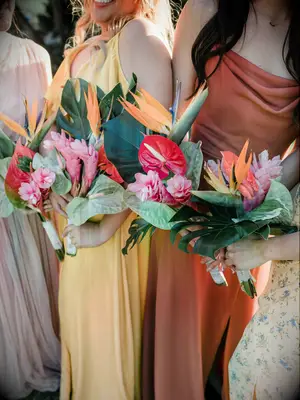 Bridesmaids hold vibrant tropical flower bouquets.