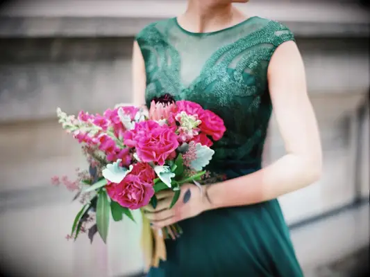 A bridesmaid holds a vibrant pink bouquet.