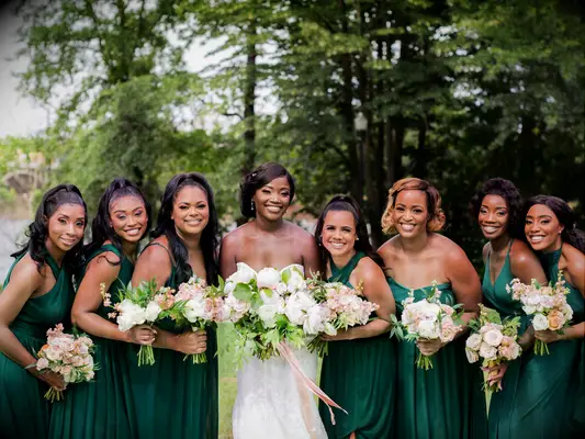 A bride and her wedding party hold pale pink and white bouquets.