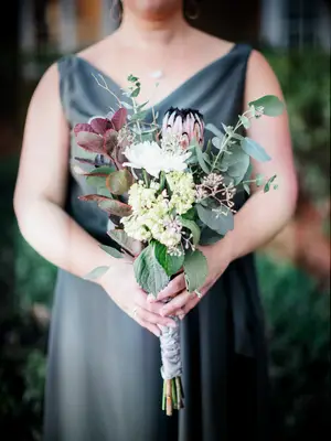 A bridesmaid holds this winter-toned floral bouquet.