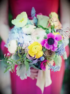 A bridesmaid holds this vibrant yellow, blue, and pink bouquet.