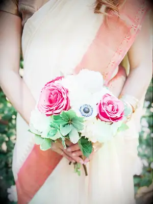 A bridesmaid holds a bright pink and white bouquet.