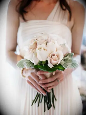 A bridesmaid holds a bouquet of pale pink roses.