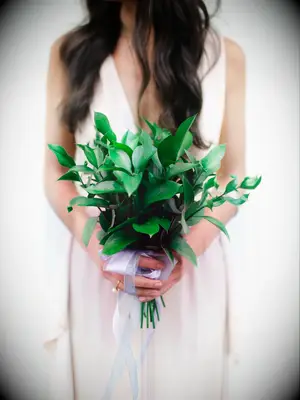 A bridesmaid holds a bouquet of vibrant greenery.