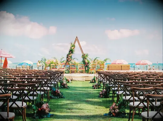 Tropical ceremony setup with wood triangle arch