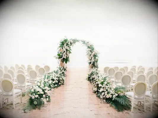 Romantic greenery arch and upholstered chairs on beach