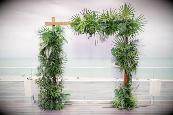 Square wedding arch covered with lush greenery. 