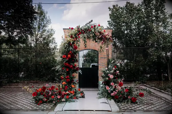 Arch in courtyard covered in red roses