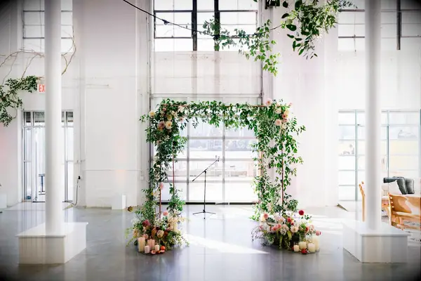 Greenery ceremony arch in white loft venue