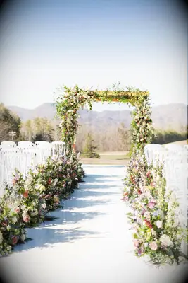 Rustic wood arch covered in loose greenery for outdoor wedding ceremony